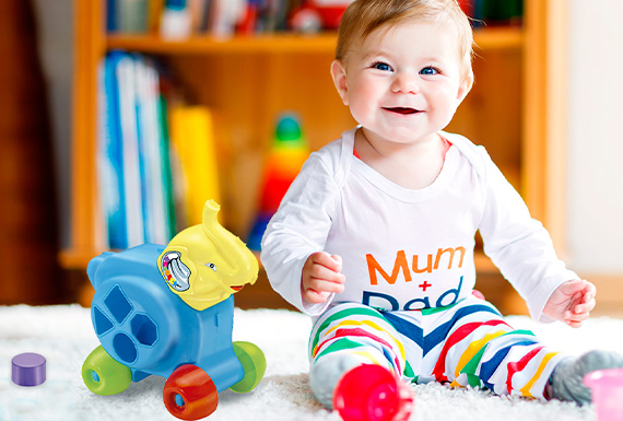 Bebê alegre com um brinquedo Tilin ao lado